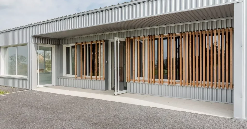 Façade moderne de la chambre funéraire avec bardage métallique et claustra en bois.
