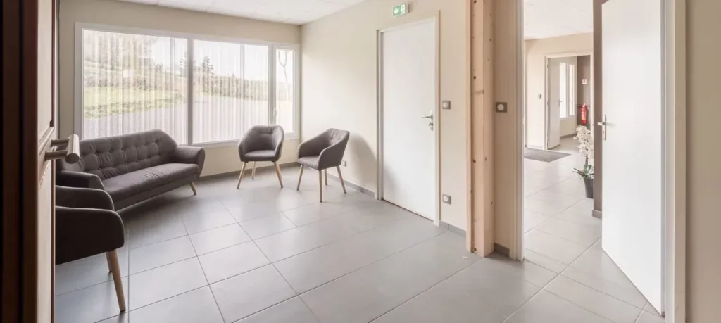 Salle d'attente lumineuse et apaisante d'une maison funéraire avec canapé et fauteuils.