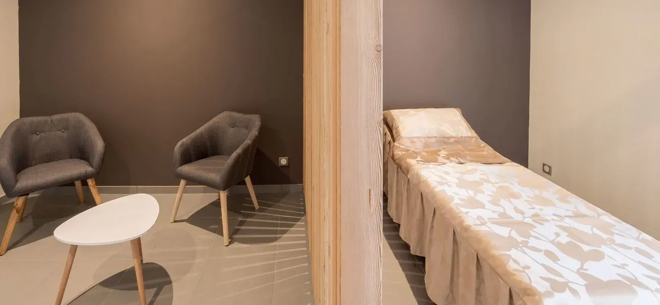 Espace de recueillement intime avec lit funéraire et coin salon séparé par un claustra.